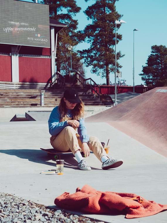 Hanna is sitting on her skateboard in the middle of the skate park.