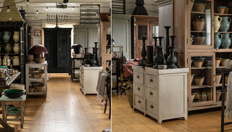 A room with a small wooden desk with a number of candlesticks standing on top, and a large display cabinet full of older clay pots and jugs.