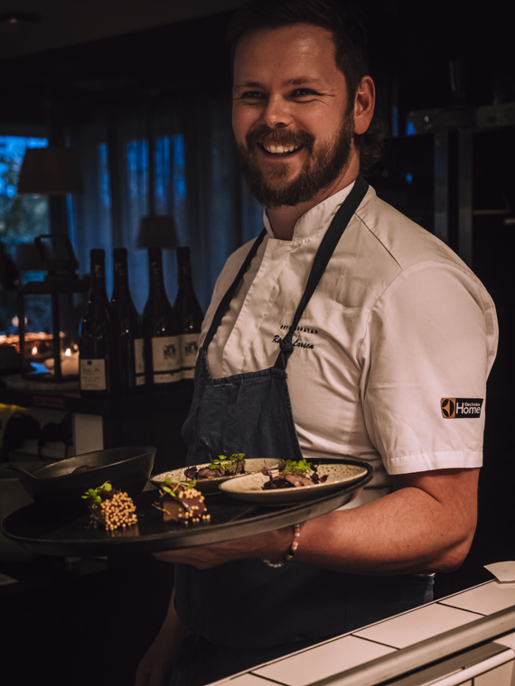 A happy Runar is just about to carry out a tray with some smaller plates where there are beautifully laid out dishes.