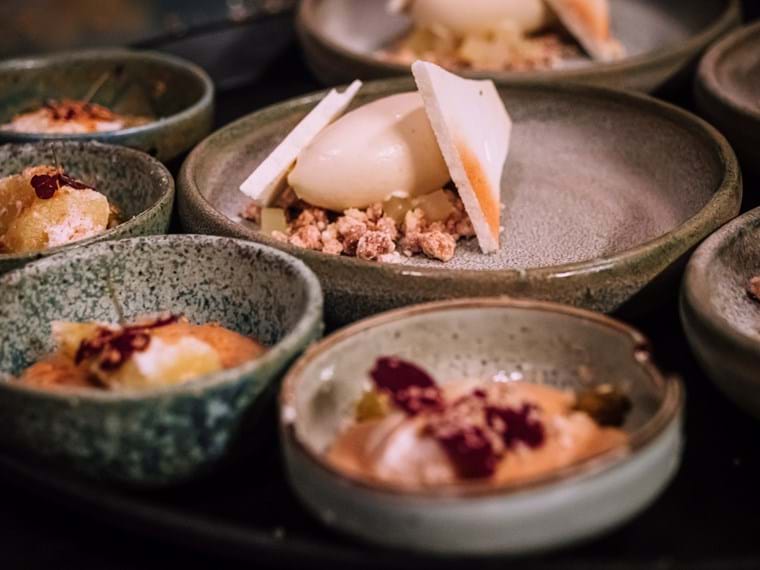 Close up of a variety of small bowls with sweet little desserts.