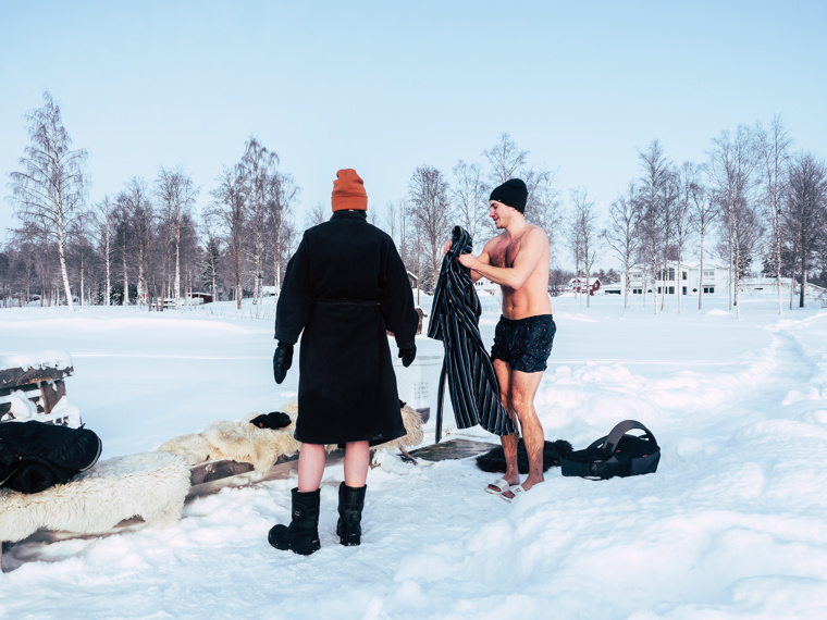 Maia has stepped out of the water and put on her bathrobe again. John takes off his bathrobe to step into the water.