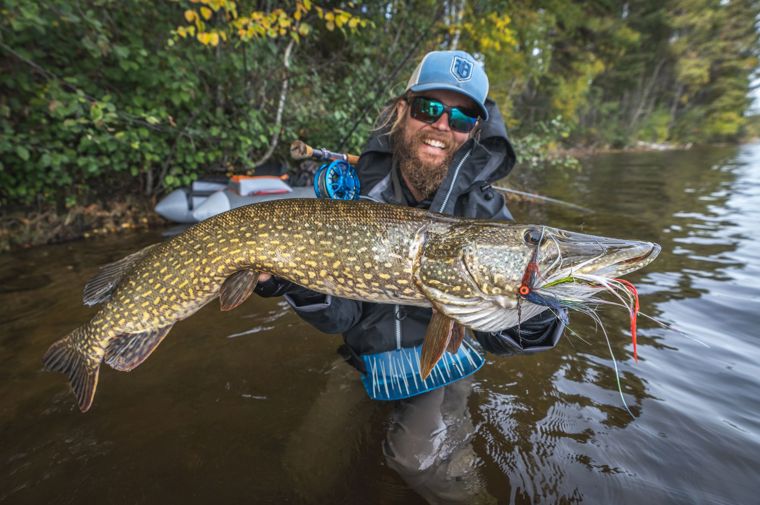 Hannes stands in the water showing off his catch, a big pike!