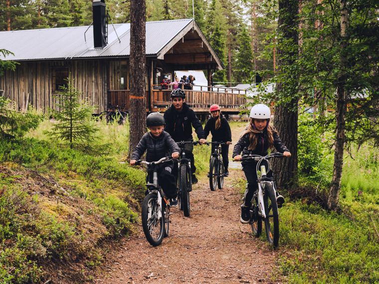 Charlotta tillsammans med familjen kommer cyklandes längs en av stigarna i skogen.