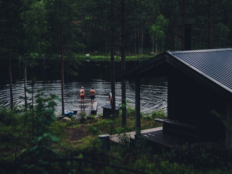 Mellan träden syns dammen där John och Matthew står ute på bryggan iklädda badkläder, redo att ta sig ett dopp. 