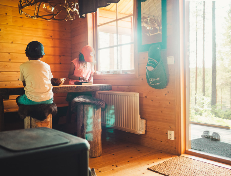 The children sit around the table inside the cottage.
