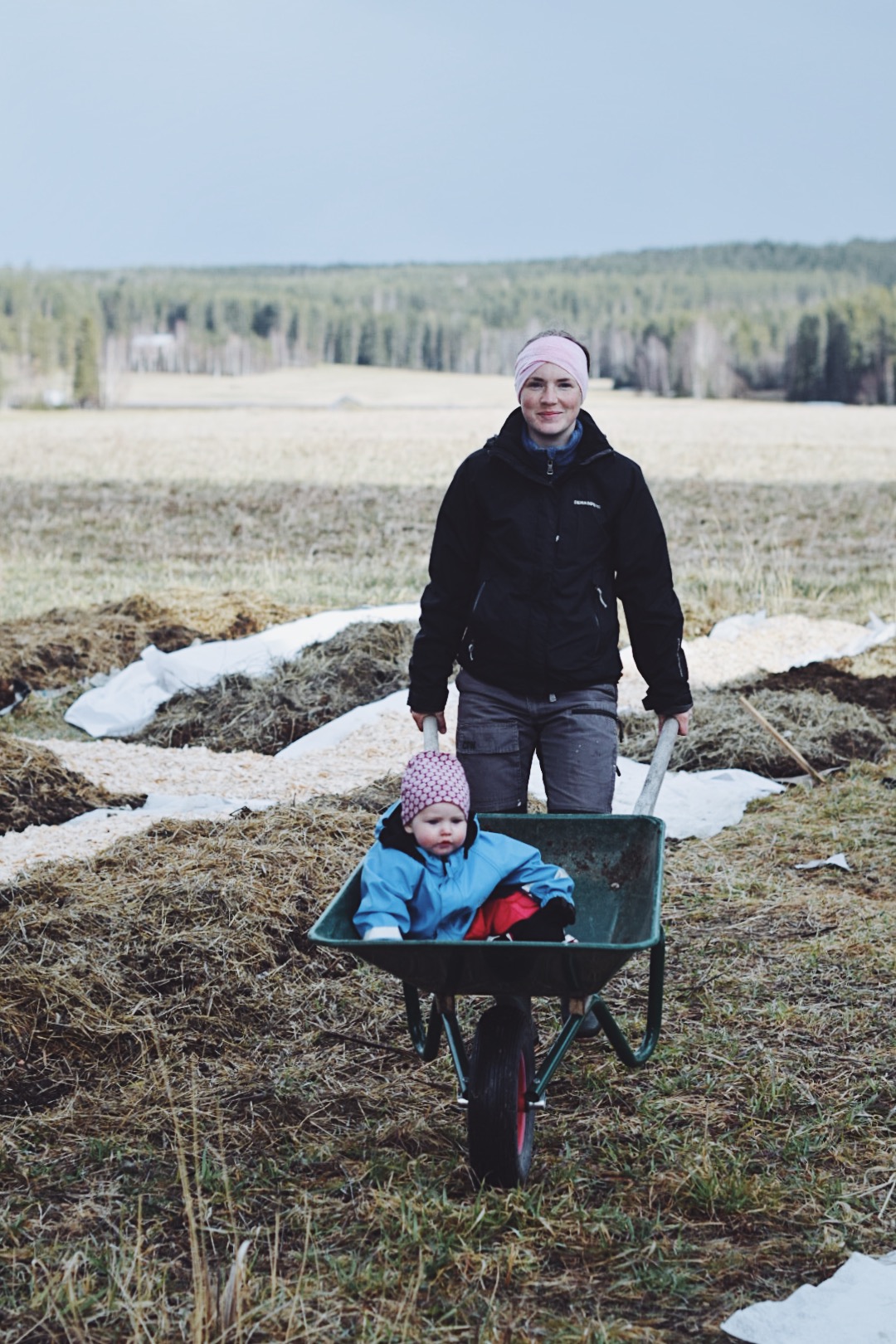 Lo sits in a wheelbarrow that Isabell shoots in front of her.